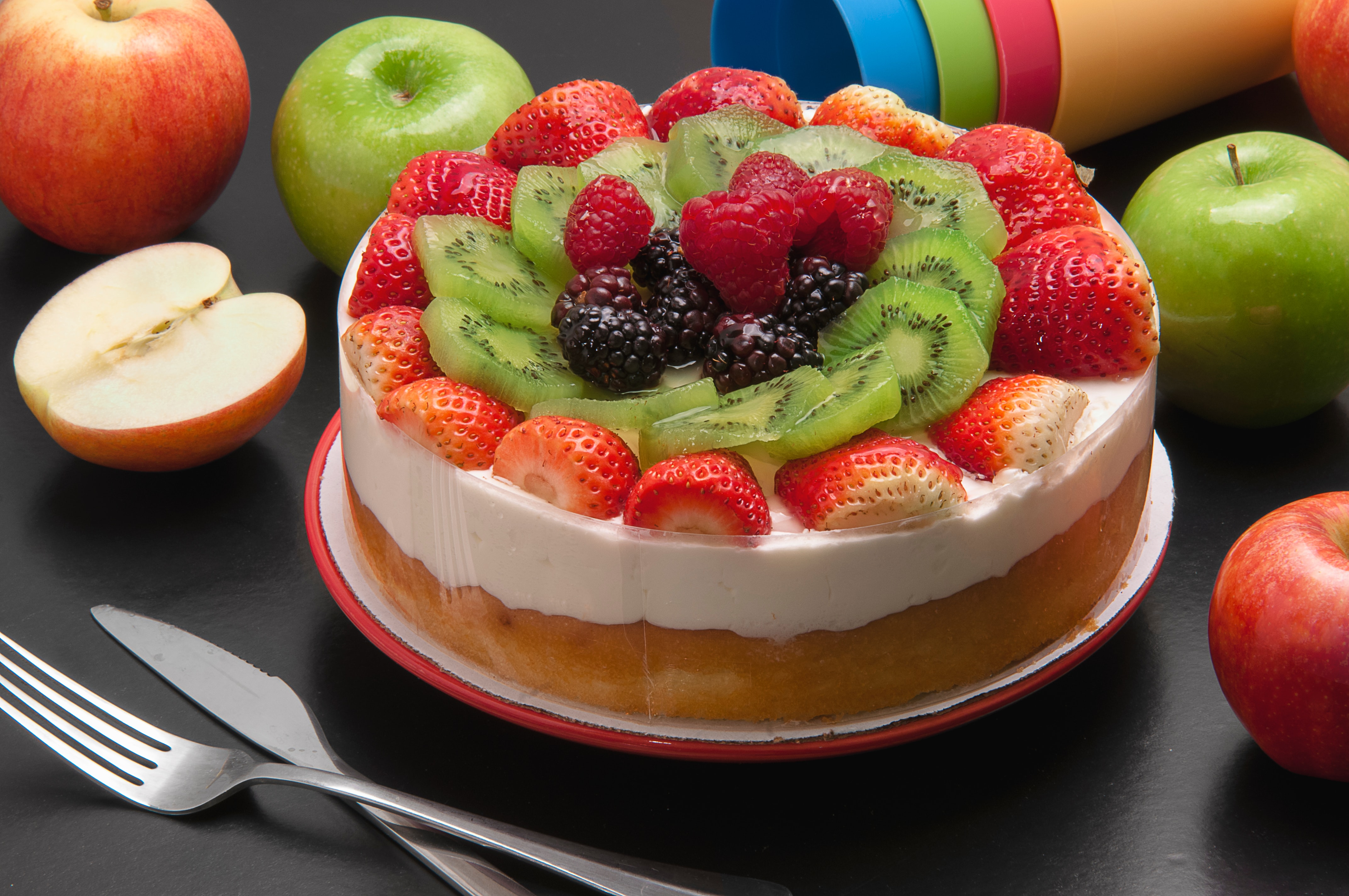 cake decorated with white icing and strawberries, kiwis, raspberries and blackberries on top
