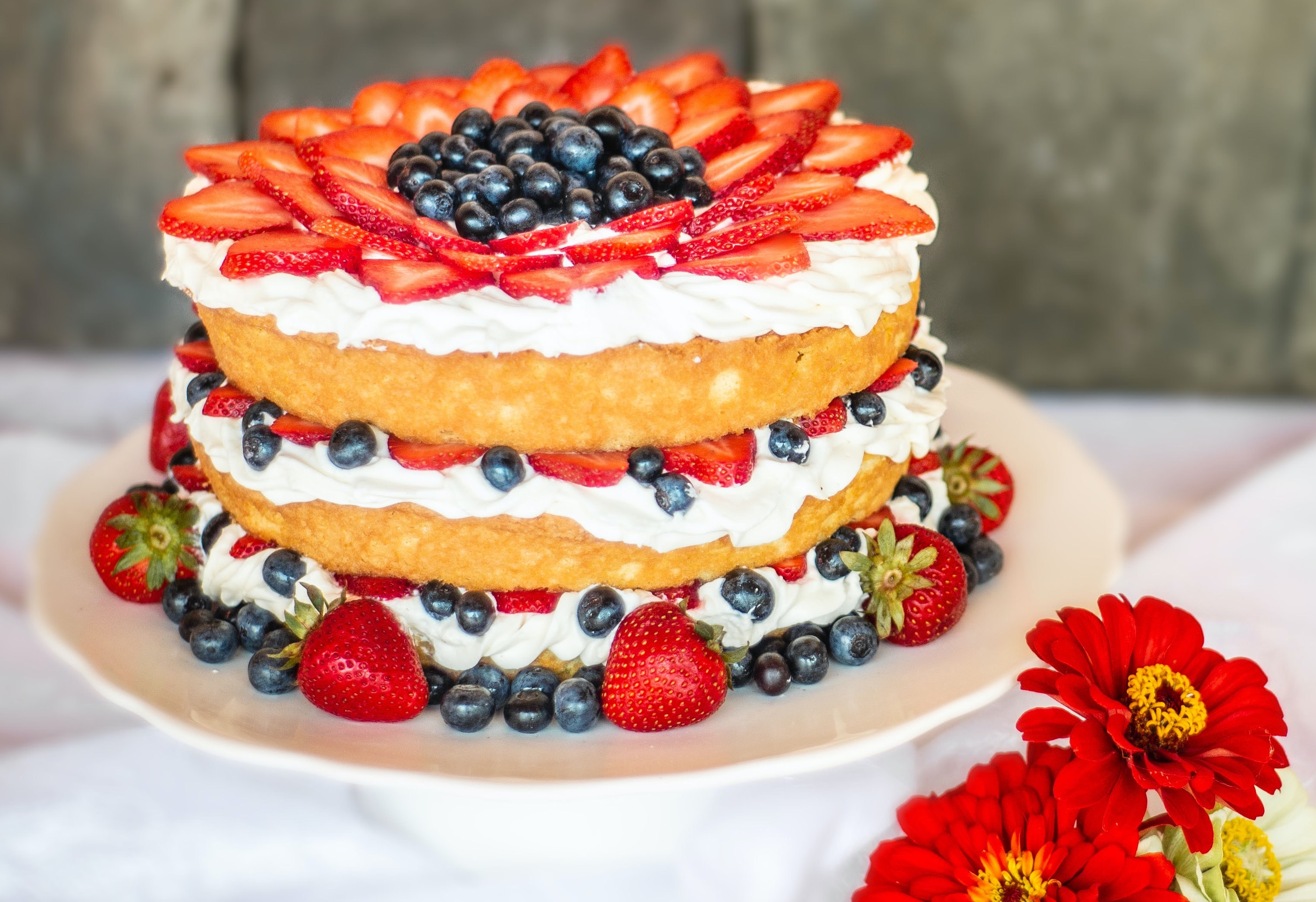 three layered cake beautifully decorated with icing, strawberries and blueberries